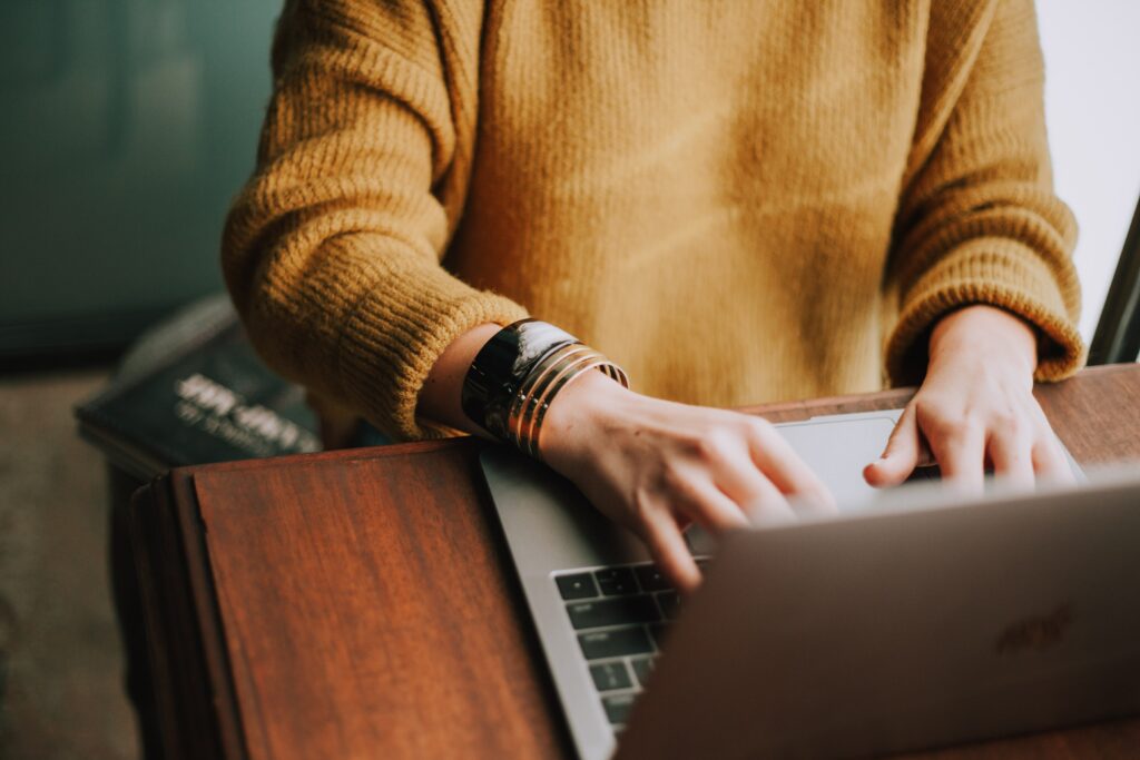 woman working on her laptop in a gold sweater