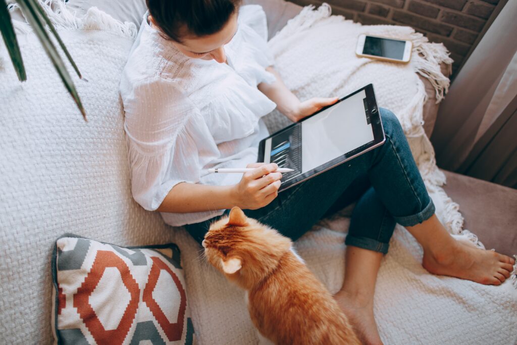 Woman working on ipad with cat nearby, 10 blog ideas for photographers