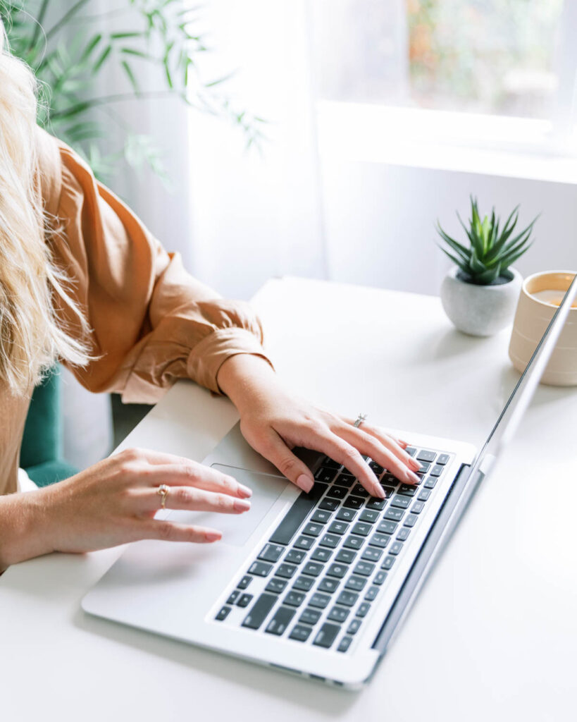 woman typing on laptop keyboard in brown shirt, web design for small businesses that are women-led