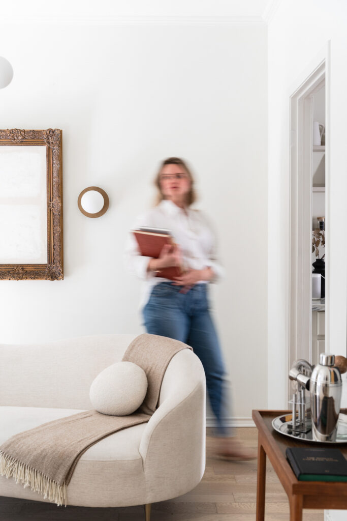 strategic web design for creative women, woman walking across living room holding books