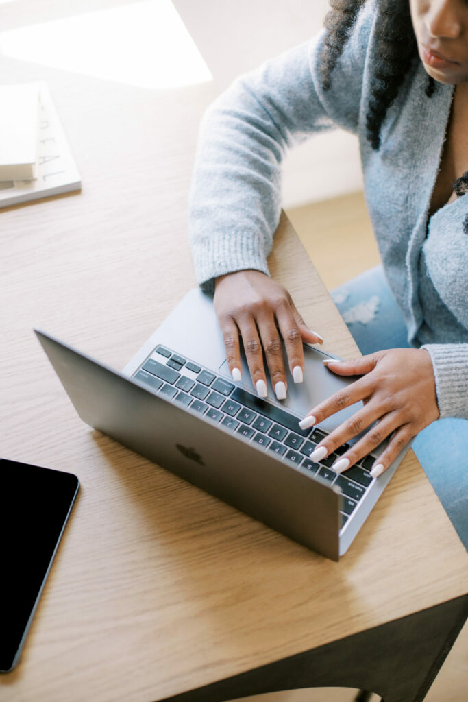 Woman in blue sweater working on laptop in home office